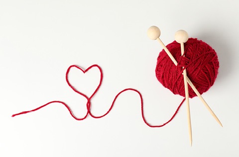 knitting needles and wool with a string in the shape of a heart