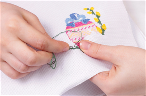 Child hands stitching into cloth