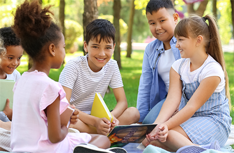 kids sitting together outside with a book