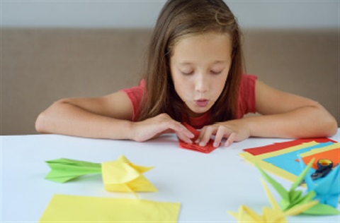 Child folding paper into origami