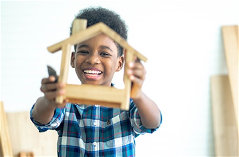 Child holding up a wooden house